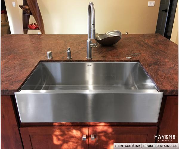 Brushed Stainless steel farmhouse apron front sink with a brushed finish. Handcrafted from 16 gauge stainless steel and installed under red quartz. 